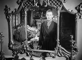 Dead of Night; Peter Cortland (Ralph Michael) gazes through the mirror to another place.